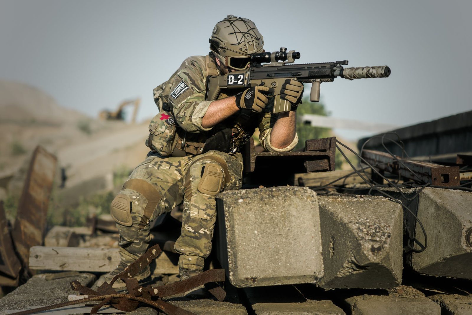 soldier near concrete pillars holding semi automatic gun with scope