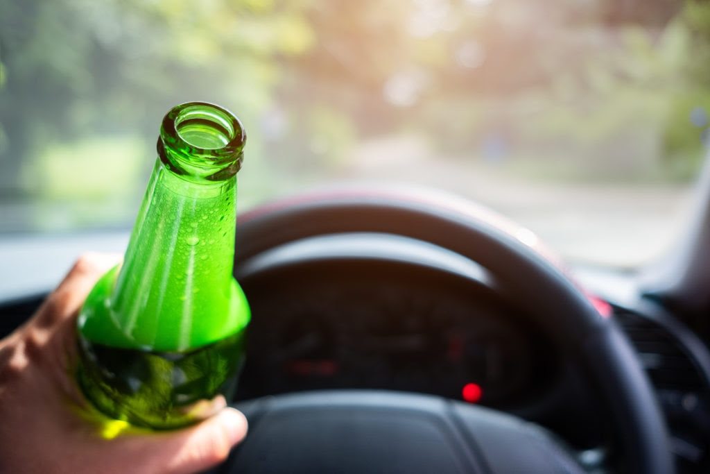 Kierowca samochodu z alkoholem w ręku. Wydmuchał 0,7 promila